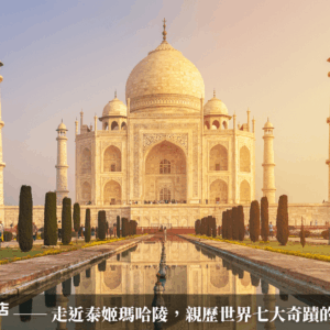 這張圖片呈現印度著名地標泰姬瑪哈陵（Taj Mahal）的正面全景。建築以白色大理石打造，配有圓頂與四座高塔，左右對稱地矗立於藍天與夕陽映照下。前方水池與花園反射建築輪廓，增添莊嚴寧靜氛圍。圖片下方搭配「印度旅遊專賣店」品牌標誌與行銷文案，強調這座世界七大奇蹟背後的動人愛情故事。