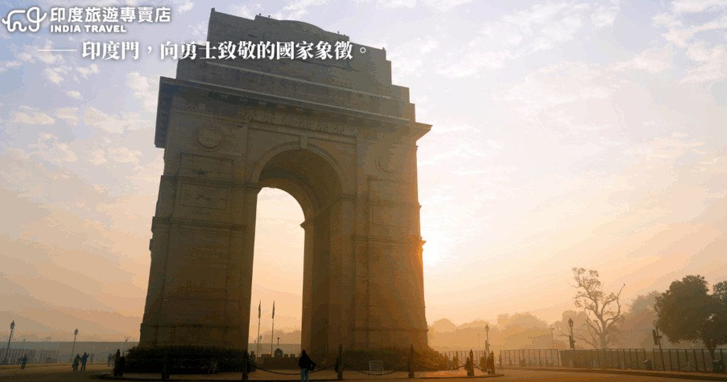 這張照片拍攝的是印度門（India Gate），拱門在晨霧與柔和日光下顯得莊嚴而靜謐。印度門是為紀念第一次世界大戰中陣亡的英印軍人而建，象徵著對英勇將士的敬意與國家記憶。畫面中可見幾位民眾與遊客在拱門周圍散步，襯托出紀念性與生活感並存的場景。整體色調溫暖、氛圍靜謐。