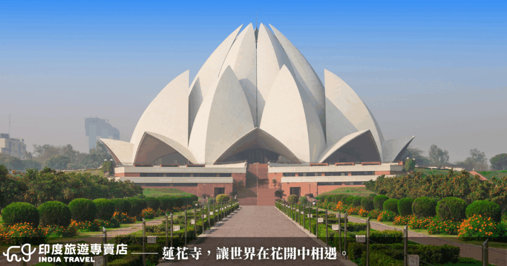 圖中為德里的蓮花寺（Lotus Temple），以白色花瓣狀建築聞名於世，是巴哈伊信仰的代表性聖殿。構圖中蓮花形體與四周的水池交織成詩意畫面，象徵寧靜與包容。此寺不分宗教信仰皆可自由進入，是一處凝聚信仰與和平的場所。圖片氛圍清新祥和，特別適合搭配心靈療癒、宗教建築或現代建築主題文章。