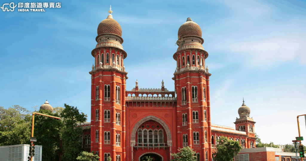畫面展示印度欽奈（Chennai）的「馬德拉斯高等法院」（Madras High Court），這座建於19世紀的殖民時期建築以鮮明的紅磚外牆與對稱的尖塔設計聞名。其獨特的印-薩拉森式建築風格融合了印度與哥德式元素，圓頂與雕花細節凸顯濃厚歷史氛圍。天空湛藍襯托出高聳的塔樓，成為南印度最具代表性的地標之一。左上角印有「印度旅遊專賣店 India Travel」的標誌，適合用於旅遊宣傳或文化介紹相關內容。