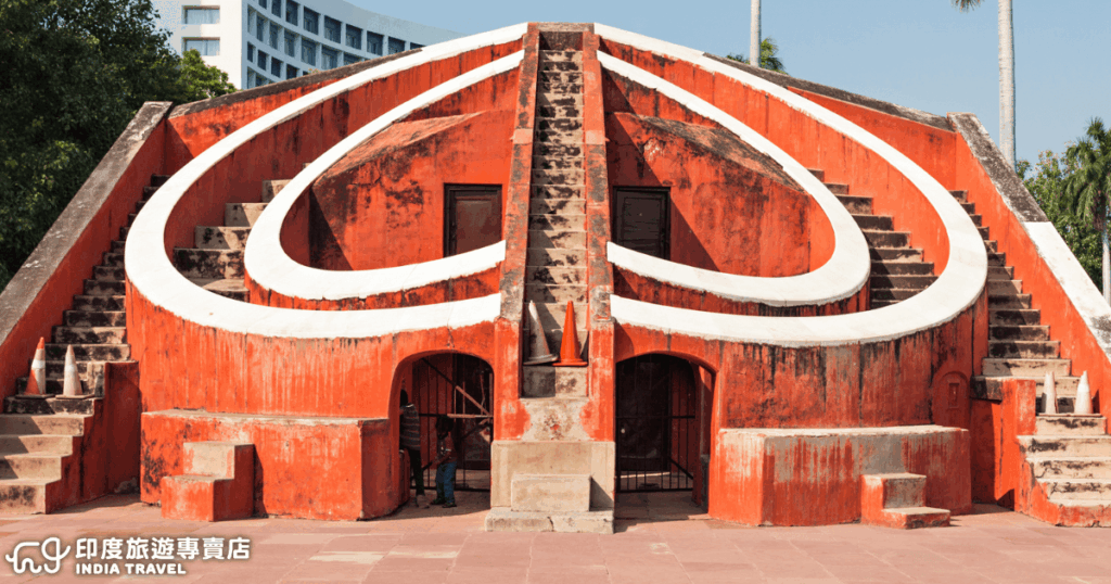 這張照片展示了位於印度德里(Delhi)的簡塔曼塔(Jantar Mantar)天文觀測台,鮮紅色的建築外觀搭配白色曲線標記,形成強烈視覺效果。這座建於18世紀的天文儀器用於觀測天體運行,是印度古代智慧與科學成就的代表。畫面中階梯與弧形結構象徵古人對天空的探索,結合歷史與建築藝術的獨特風貌。